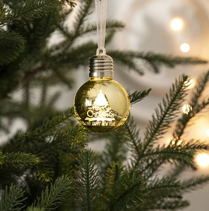 Warm gold Christmas bulb ornament with Merry Christmas lettering on a festive tree
