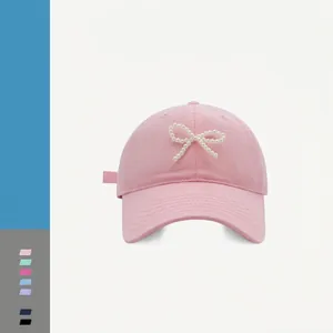 Close-up of pink baseball cap with pearl bow decoration and cotton twill texture details