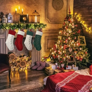 Dettaglio di quattro calze di Natale in maglia appese a un caminetto decorato a festa