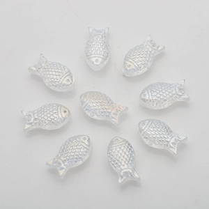 Macro shot of 10 clear iridescent fish-shaped acrylic beads arranged on a white background