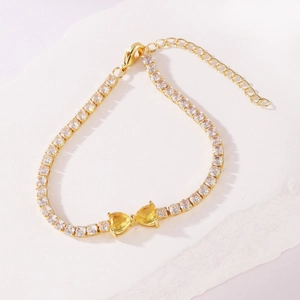 Detail showing yellow heart-shaped cubic zirconia butterfly bow on gold tennis bracelet