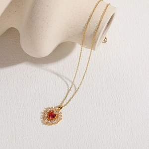 Dettaglio del ciondolo a fiore con zircone a cuore rosso e catena placcata oro 14K