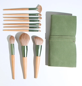 Detailed set of 11 professional makeup brushes with wooden handles and green storage bag