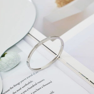 Macro detail of silver stainless steel bangle with pavé zircons on white background