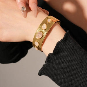 Détail du bracelet jonction doré avec goutte en résine et pierres précieuses polies