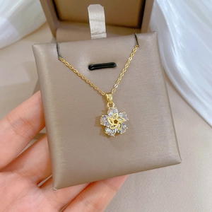 Rotating flower pendant necklace in gold finish with sparkling crystals on a jewelry box