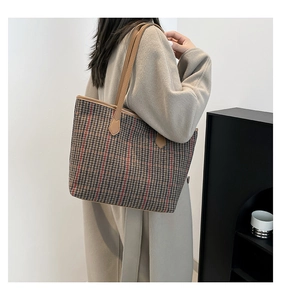 Close-up of vintage houndstooth tote bag with red accents and brown leather strap