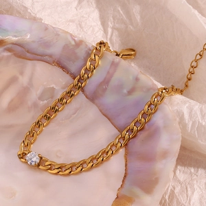 Detail of 18K gold-plated curb chain bracelet featuring a round-cut cubic zirconia