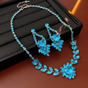 Detailed view of silver necklace and earrings set featuring blue heart crystals and leaf accents