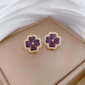 Elegant gold clover stud earrings with purple heart crystals and zircon pavé detailing