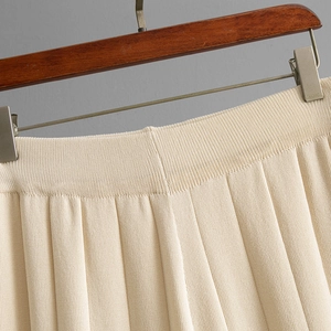 Detailed macro shot of high-waist pleated design and elastic waistband on beige knit pants