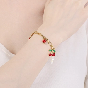 Bracelet doré avec breloques cerise et perle au poignet pour un style pastoral élégant