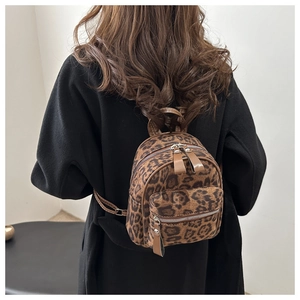 Nahaufnahme des Mini-Rucksacks mit Leopardenmuster und Leder-Reißverschlüssen am Model
