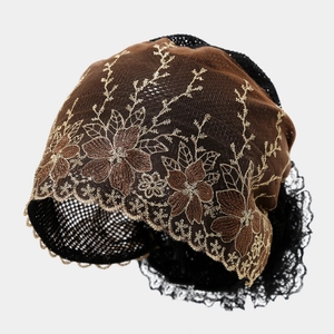 Detail of coffee lace turban with intricate golden floral embroidery and wavy edges