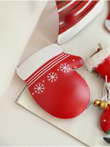Detail eines roten Metallhandschuh-Weihnachtsanhängers mit weißen Schneeflocken Mustern