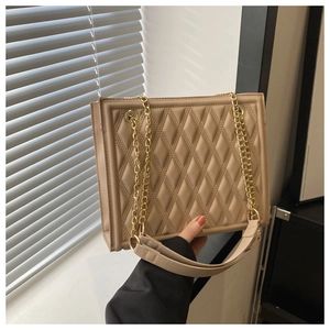 Detailed macro view of the beige quilted chain bag featuring gold metal hardware and texture