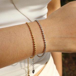 Close-up of gold and silver olive bead bracelets with adjustable chains on a wrist