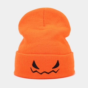 Detail der orangefarbenen Strickmütze mit schwarzer Kürbis-Teufels-Stickerei am Umschlag
