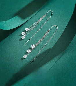Macro shot of 925 sterling silver tassel earrings with three drop-shaped zircons on green