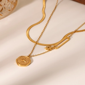 Detail of layered gold snake chain and star pendant with geometric clasp decoration