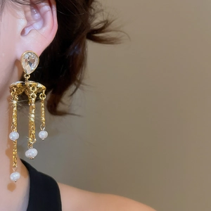 Close-up of elegant gold tassel earrings with pearls and crystals worn by a model