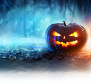 Macro shot of Halloween pumpkin lantern with warm light on forest ground with leaves