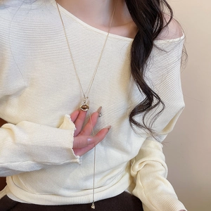 Close-up of golden Y-shaped long necklace with heart geometric pendant on model