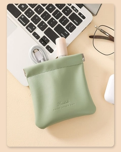 Flat lay of a green PU leather pouch with squeeze closure on a desk with tech accessories