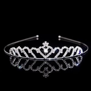 Macro shot of silver bridal crown with sparkling heart rhinestones on reflective black surface