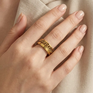 Détail d'une bague large dorée avec chiffres romains et texture de chaîne élégante