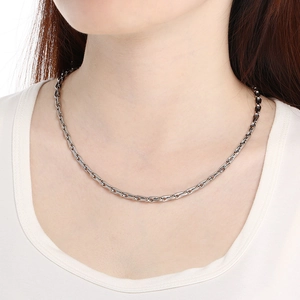 Close-up of a silver stainless steel pig nose chain necklace worn by a model
