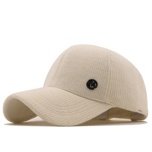 Minimalist beige waffle knit baseball cap with M logo detail in a 45-degree side view