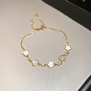 Detail of adjustable gold-plated bracelet featuring white enamel flowers and cubic zirconia