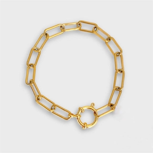 Close-up of golden paperclip chain bracelet featuring a large round spring clasp detail