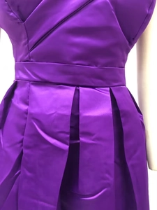 Detail eines lila Satinkleides mit eleganten Taillenfalten und glatter Stoffstruktur
