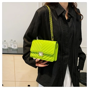 Detail shot of neon green quilted chain bag worn by a model in a warm indoor setting