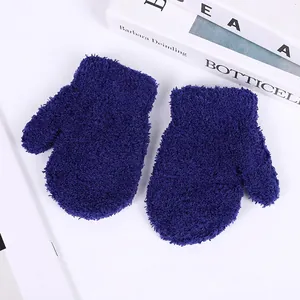 Detailed close-up of dark blue coral fleece winter mittens for children on a white desk