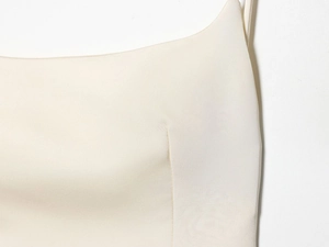 Detailed close-up of cream-white woven fabric and reinforced stitching on a satin dress
