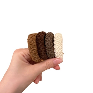 Elastic knit hair scrunchies set in neutral earth tones held on hand with white background