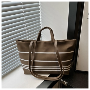 Macro detail of the brown canvas tote bag featuring horizontal white stripes and dual straps