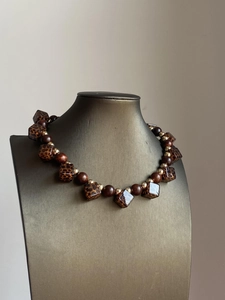 Detail view of retro leopard print resin beads and gold accents on a choker necklace