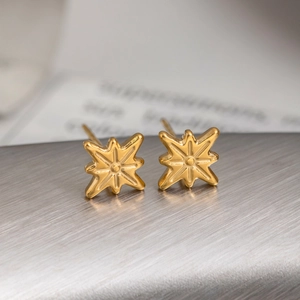Pair of gold stainless steel octagonal star stud earrings on a brushed metal surface