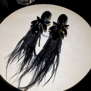 Macro shot of gothic black feather tassel earrings with sparkling rhinestones and dark gems