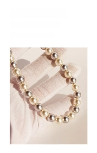 Detailed macro view of round champagne gold, silver grey, and white pearl necklace strand