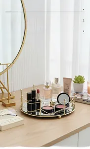 Detail of round gold mirror tray with wavy frame and cosmetics on wooden table