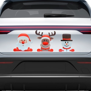 Close-up of reflective Santa Reindeer and Snowman magnetic decals on a white car rear