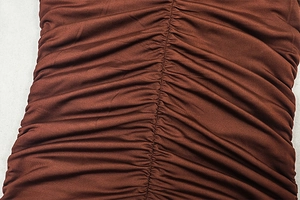 Close-up of ruched detail and soft fabric texture on a rust-brown bodycon dress