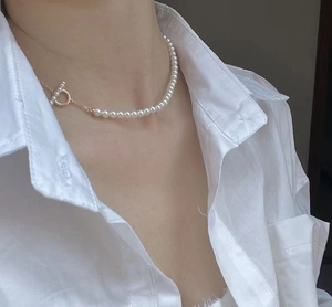 Nahaufnahme eines Models mit Perlenkette und dekorativem goldenem OT-Knebelverschluss