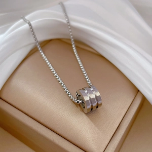 Detail of silver cylindrical pendant with Venetian box chain on silk background