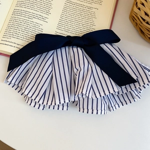 Detailansicht des gestreiften Haargummis mit blauer Satinschleife auf einem Vintage-Buch